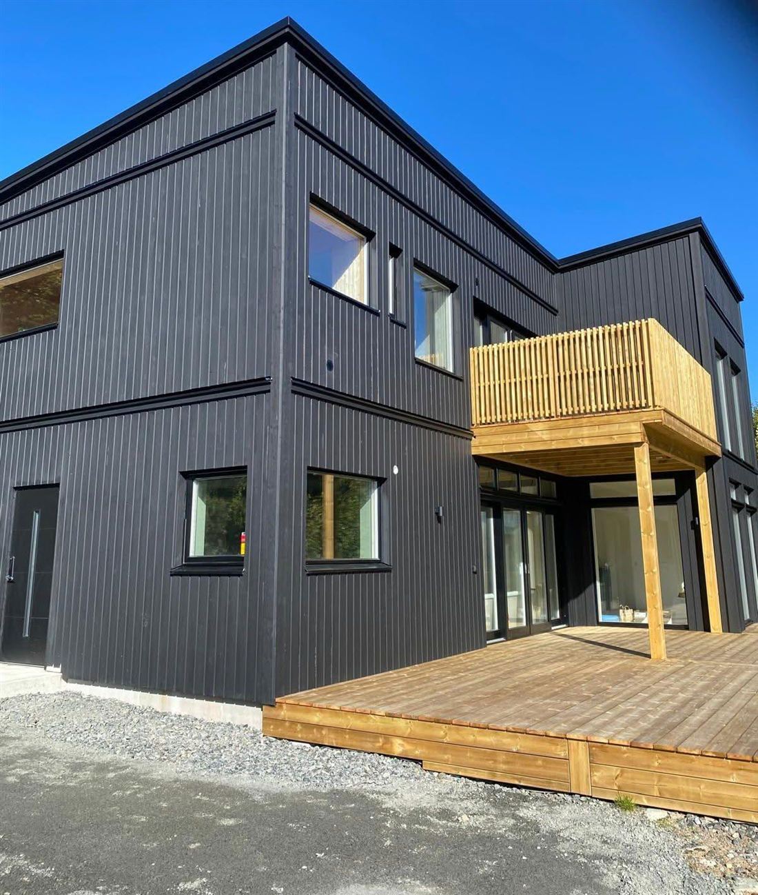 Svart träklädd villa med balkong och trädäck